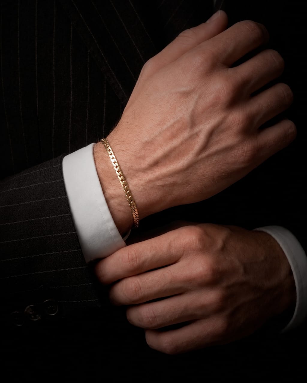 Pulsera cubana plana de oro amarillo de 18K puesta, con eslabones de tejido cubano clásico pulidos a espejo.