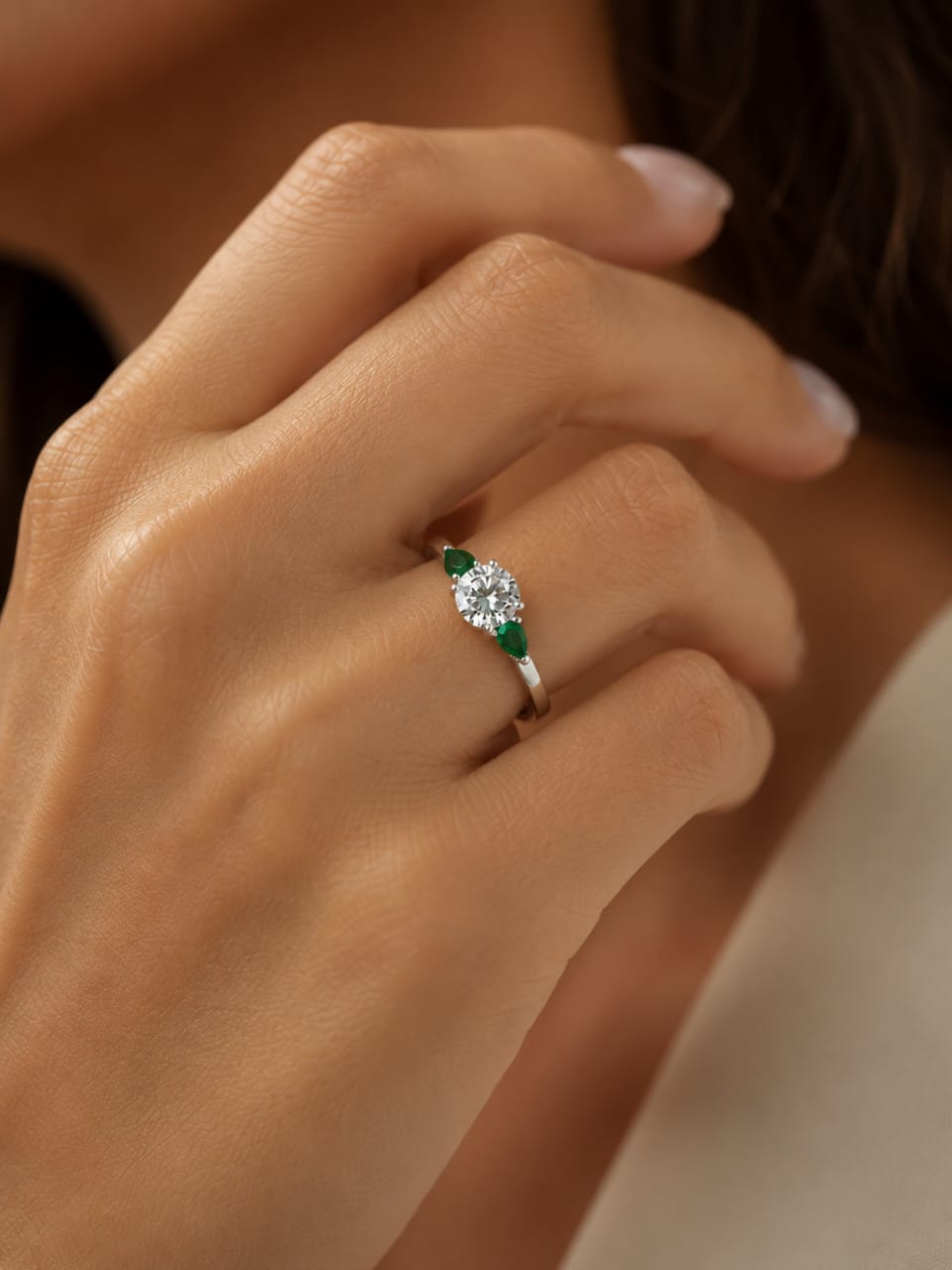 Anillo de compromiso de oro blanco de 18K modelo Garden con brillante natural central de 1.16 carats y esmeraldas naturales laterales en corte pera.